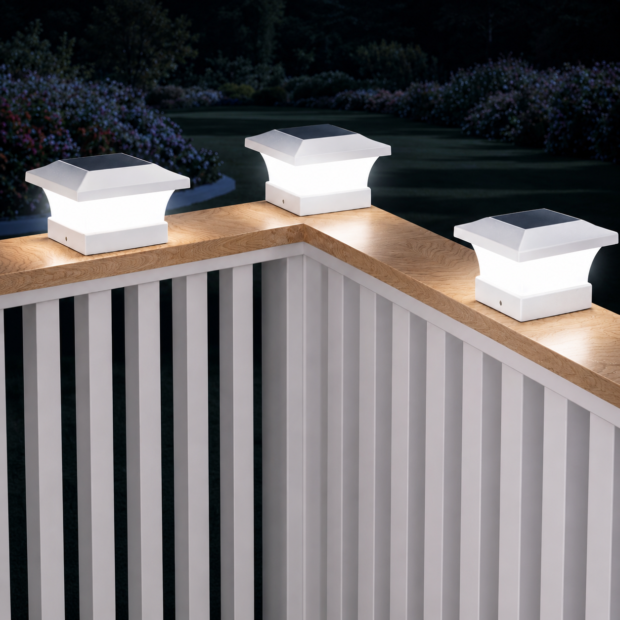 Drei Solar-Pfostenleuchten beleuchten ein modernes Terrassengeländer bei Nacht.

