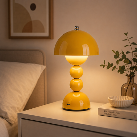 Gelbe kabellose LED-Tischlampe im nordischen Retro-Design auf einem Nachttisch mit stimmungsvoller Warmweiß-Beleuchtung.
